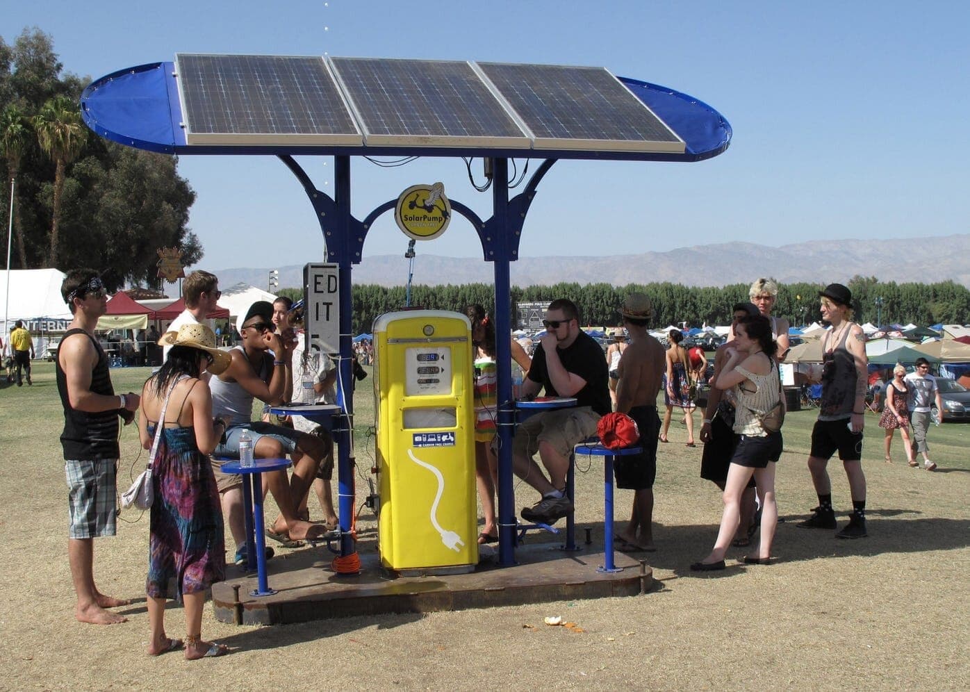 SolarPump - a repurposed vintage gas pump turned solar-powered phone charging station under a panel canopy at Coachella
