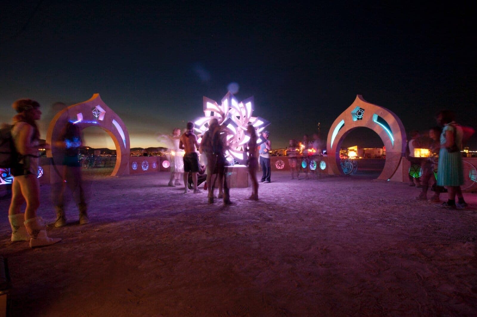 The café portal archways glowing purple across the open playa at dusk, Burning Man 2013