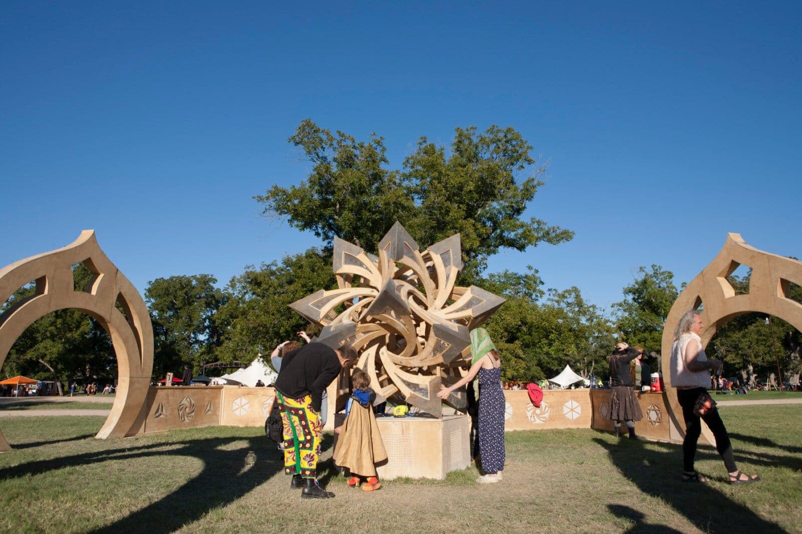 The wooden arches and star sculpture installed on green parkland at Art Outside festival, Texas