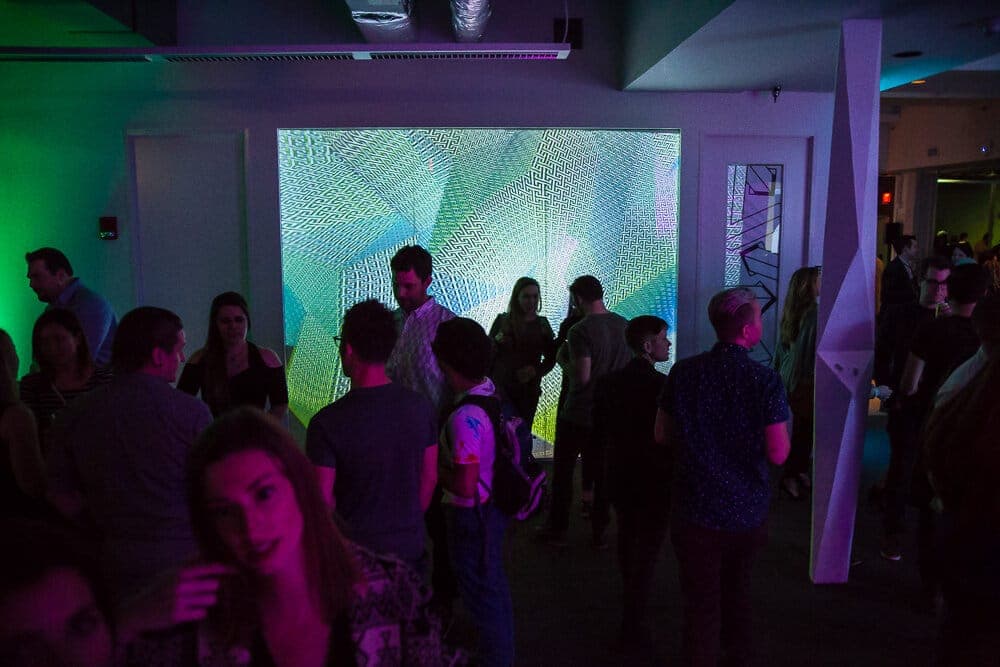 Radial burst pattern projected across the far wall of the packed party space